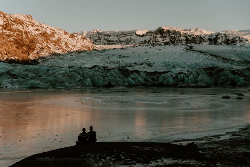 Couple sitting together and looking out over Sólheimajökull Glacier during a quiet Iceland elopement moment.