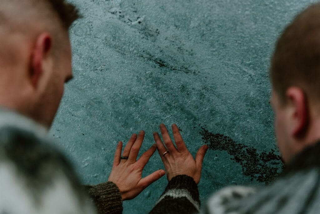 Close-up of an eloping couple touching the blue ice at Sólheimajökull Glacier in Iceland during their adventure elopement.