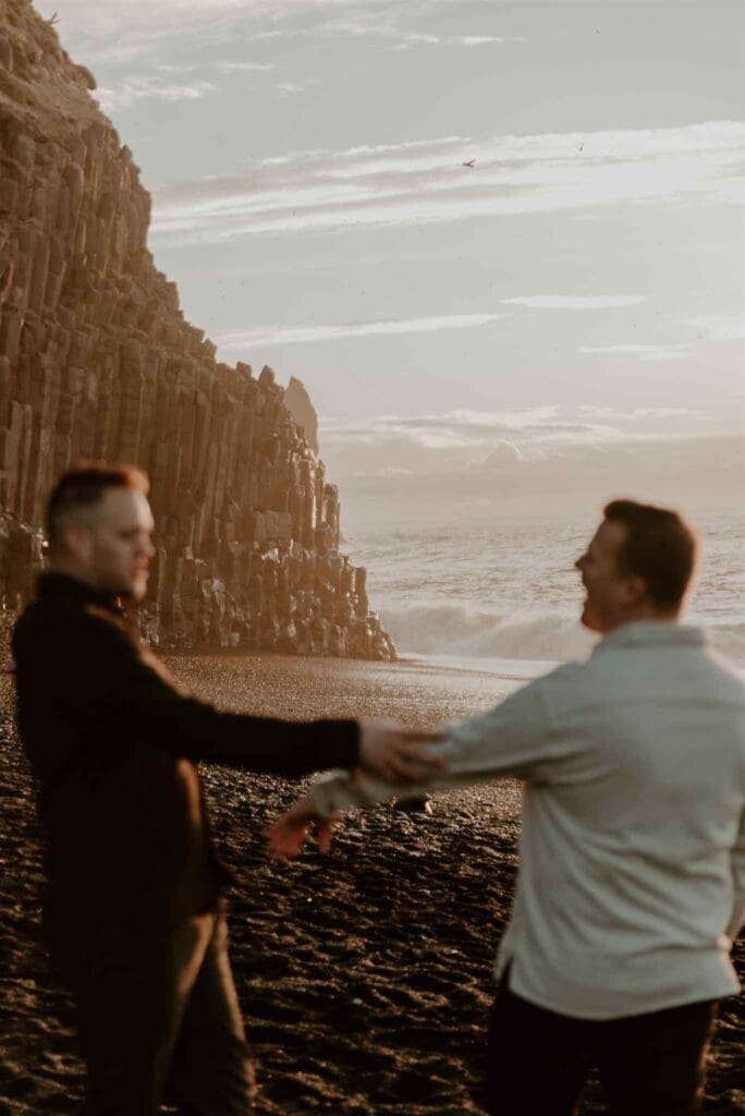 Couple flirting, with an otherworldly landscape in Iceland behind them and the ocean filling some of the frame