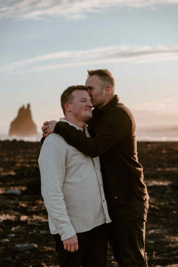 Male couple embraces at reynisfjara black sand beach