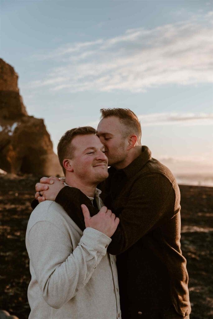 Male couple hugs at reynisfjara beach in Iceland